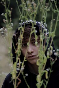 Portrait of teenage boy looking through plants