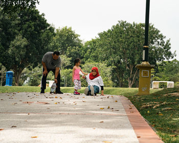 Children riding skateboard and scooter in the park.