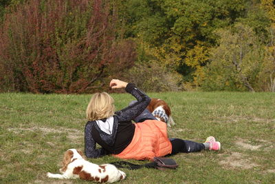 Rear view of people with dog sitting on grass