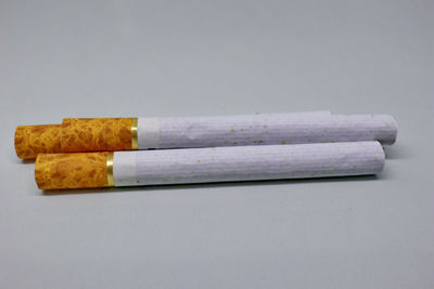 Close-up of cigarette on table against white background