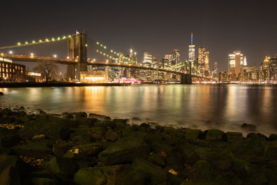 Illuminated bridge over river in city at night