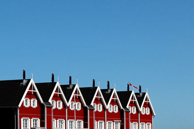 Low angle view of red building against clear blue sky