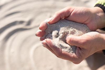 Close-up of man holding sand on beach