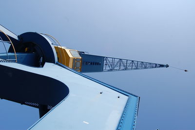 Low angle view of crane against clear blue sky