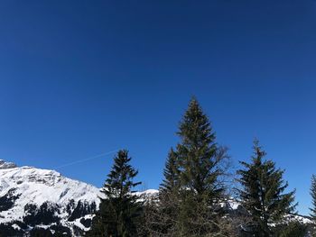 Low angle view of snowcapped mountains against clear blue sky