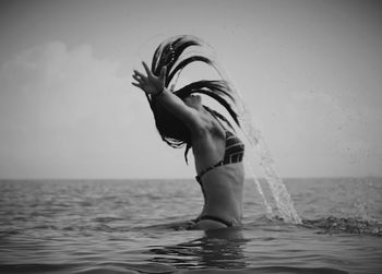 Side view of woman splashing water with hair in sea