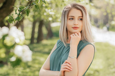 Portrait of a beautiful thoughtful woman with short blonde hair posing in a flowering spring garden