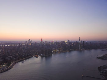 Wide aerial drone view of manhattan skyline with east river in new york city at dusk and city lights