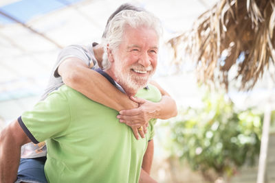 Smiling man looking away while piggybacking woman outdoors