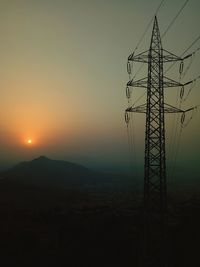 Electricity pylon against sky during sunset