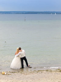 Rear view of newlywed couple standing on beach