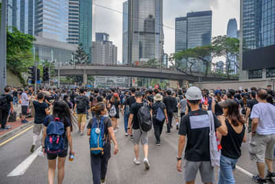 People on street by modern buildings in city