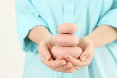 Midsection of woman holding stacked pebbles against white background