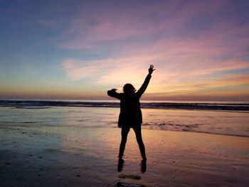 Silhouette man standing on beach against sky during sunset