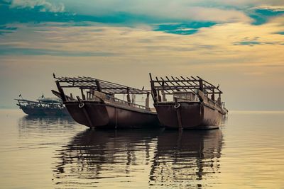 Fishing boat in sea against sky during sunset