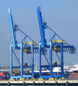 Cranes at commercial dock against sky