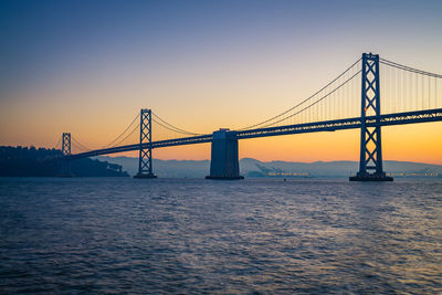 Bay bridge against clear sky at sunrise