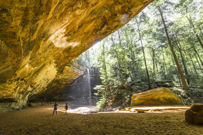 People on rock amidst trees in forest hocking hills ohio