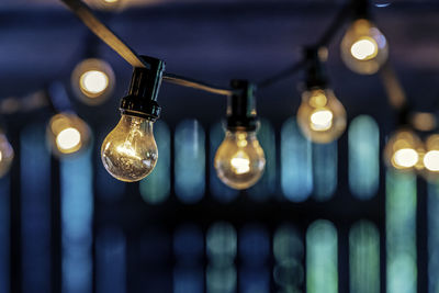 Close-up of illuminated light bulbs hanging from ceiling