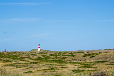 Mid distance view of lighthouse on field against sky