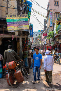 Rear view of people walking on street in city