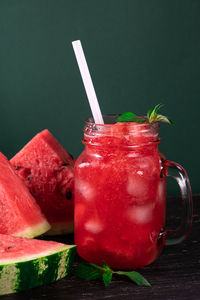 Cold watermelon smoothie and pieces of refreshment watermelon on dark background. 