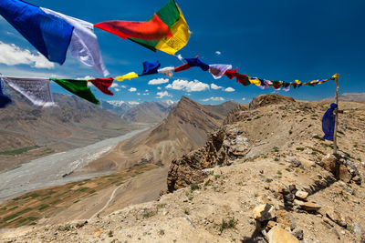 Multi colored flags hanging on mountain against sky