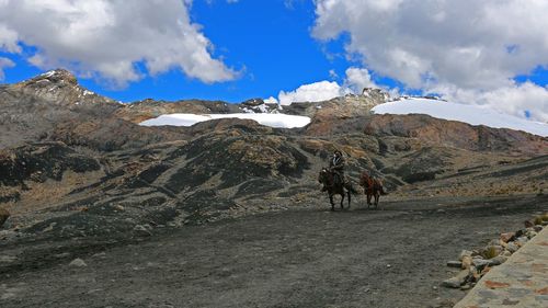 Rear view of people walking on mountain against sky