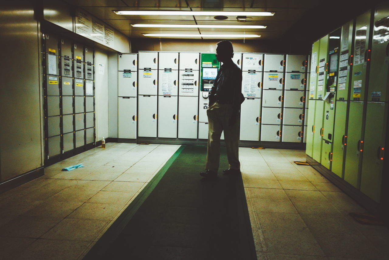 FULL LENGTH REAR VIEW OF MAN STANDING IN BUILDING