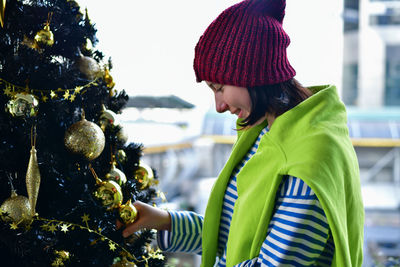 Young woman standing by christmas tree