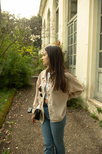 Rear view of young woman standing against trees