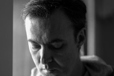 Close-up of mature man by window at home