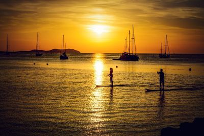 Silhouette sailboats in sea against sky during sunset