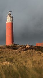 Lighthouse on field against sky