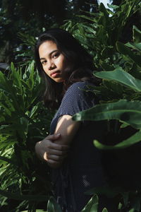 Portrait of young woman standing against plants