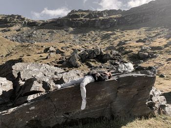 Full length of young man lying on rock formation on field