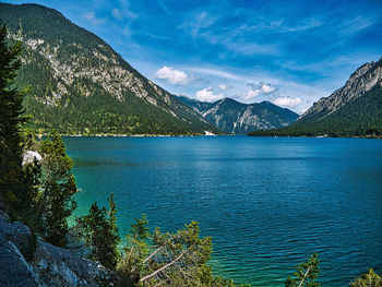 Scenic view of lake by mountains against blue sky