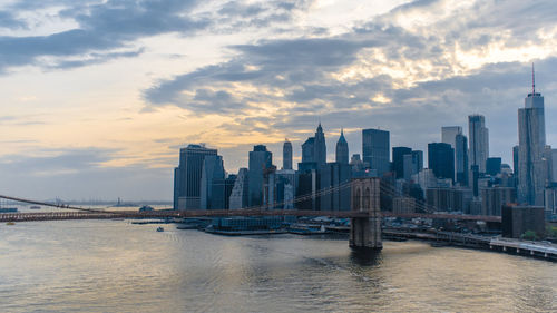 View of bridge over river by buildings against sky