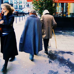 Rear view of people walking on footpath