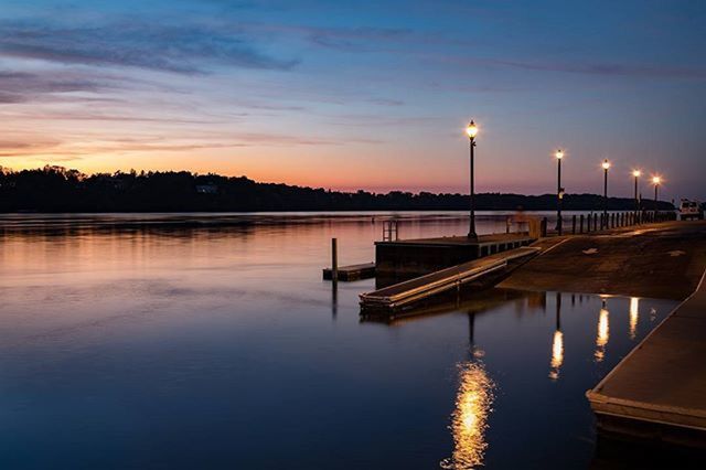 sunset, water, reflection, sky, lake, built structure, silhouette, illuminated, waterfront, scenics, tranquility, tranquil scene, architecture, river, beauty in nature, pier, nature, dusk, idyllic, street light