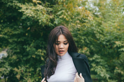 Beautiful young woman standing against trees