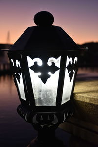 Close-up of illuminated lamp against sky during sunset
