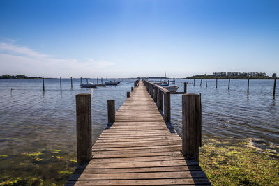 Wooden pier over lake against sky