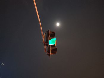 Low angle view of illuminated lighting equipment against sky at night