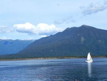 Sailboat sailing on sea against mountains