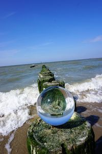 Close-up of beach by sea against sky