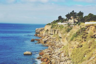 Scenic view of sea by cliff against sky