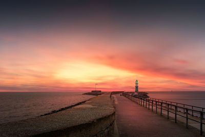 Pier on sea against sky during sunset