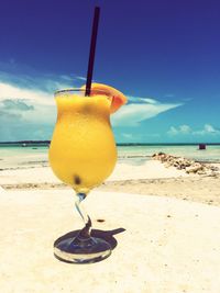 Close-up of beer on beach against sky