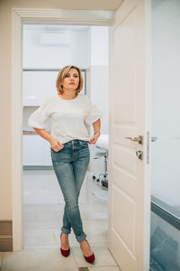 Portrait of a beautiful slender woman in full growth in the doorway of a bright medical office. the